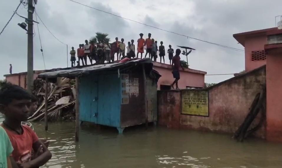 बाढ़ से जलमग्न गांव के ग्रामीण विद्यालय की छत पर शरण लेने पैर मजबूर,राहत कार्य धीमे के कारण लोग पलायन को मजबूर